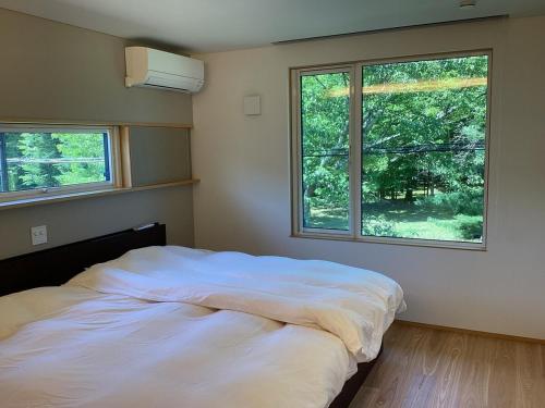 a bedroom with a large white bed with two windows at Le Repos軽井沢 in Karuizawa