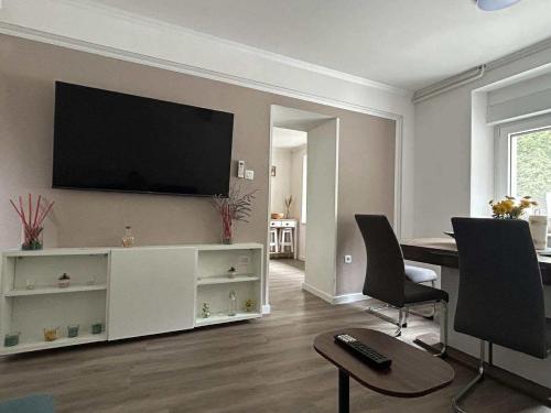 a living room with a table and a television on a wall at Apartment Tonc in Kobarid