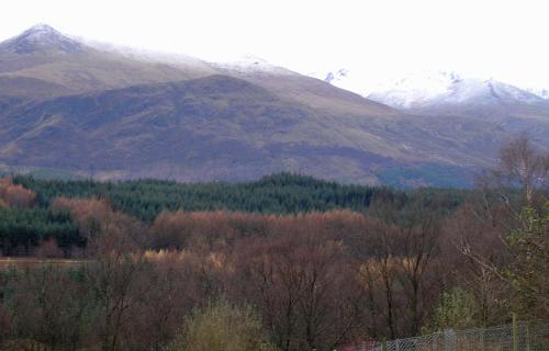 a mountain range with trees and snow covered mountains at Achnabobane Farmhouse in Spean Bridge