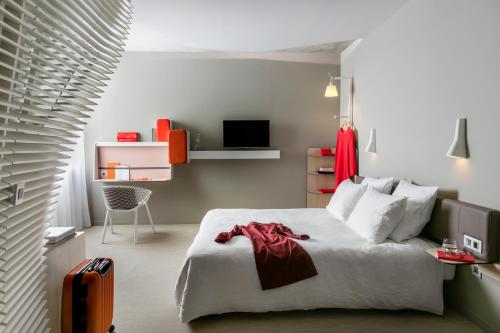 a hotel room with a bed and a chair at OKKO Hotels Bayonne Centre in Bayonne