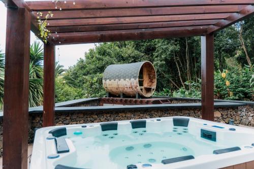 a hot tub on a patio with a pergola at Azores Casa da Mata wellness Spa in São Vicente Ferreira