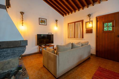 a living room with a couch and a tv at Azores Casa da Mata wellness Spa in São Vicente Ferreira