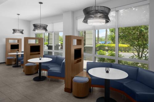 a waiting room with tables and chairs and windows at Courtyard by Marriott Orlando South/Grande Lakes Area in Orlando
