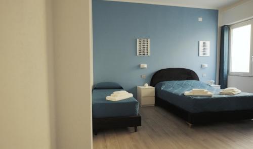 two beds in a room with blue walls at Mhometredici Guest House in Sestu
