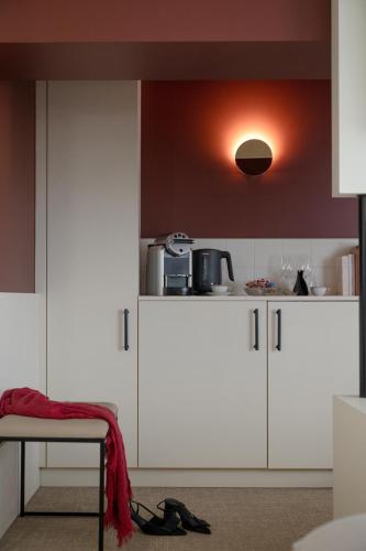 a kitchen with white cabinets and a microwave on the wall at MiHotel - Rue Cuvier in Lyon