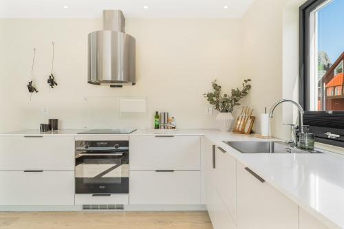a white kitchen with a sink and a stove at Spectacular mountain views with fireplace and jacuzzi in Svolvær