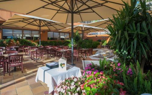 a restaurant with tables and chairs and umbrellas at Rosamar & Spa 4*s in Lloret de Mar