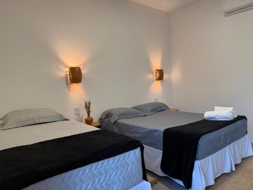 a bedroom with two beds and two lights on the wall at Pousada Casa da Kátia Lagoa do Cassó in Mata Grande
