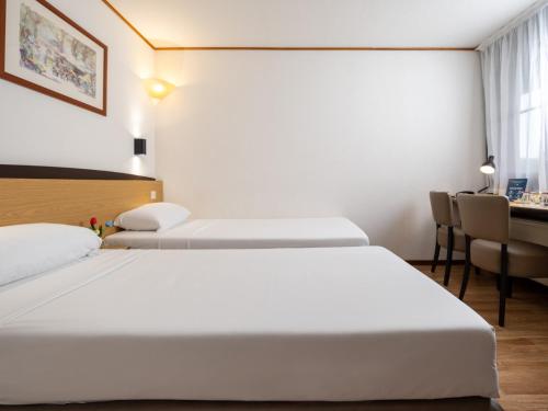 a hotel room with two beds and a desk at Campanile Hotel & Restaurant Gent in Ghent
