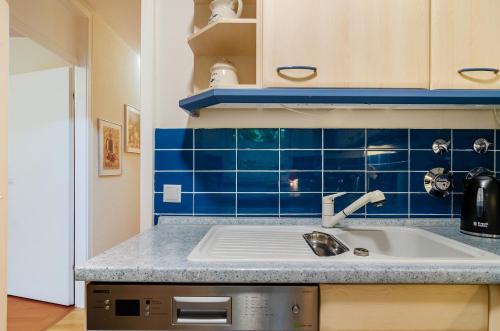 une cuisine avec un évier et un mur carrelé bleu dans l'établissement Ferienwohnung Schmälzle, à Braunlage