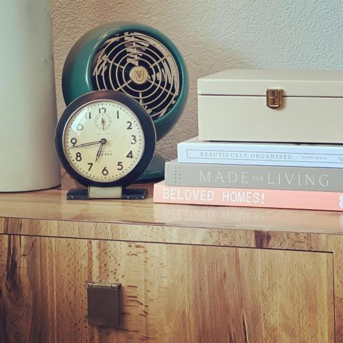 une horloge assise sur une étagère avec des livres dans l'établissement Fernando Flats, à Palm Beach Shores