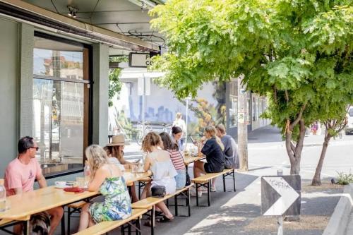 a group of people sitting at tables outside a restaurant at Cosy Footscray Studio - 2 Guests in Melbourne