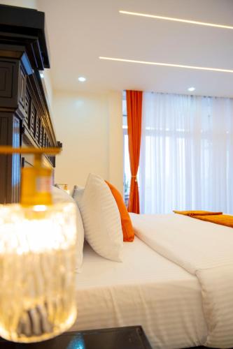 a bedroom with a bed with white sheets and orange pillows at LUMI R Boutique Hotel in Kigali
