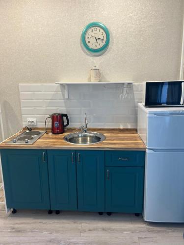 una cucina con un lavandino e un orologio a parete di Happy House a Karagandy