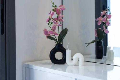 a black vase with flowers on top of a dresser at Elegant Comfort Pool Gym & Kids Club in Mohammedia