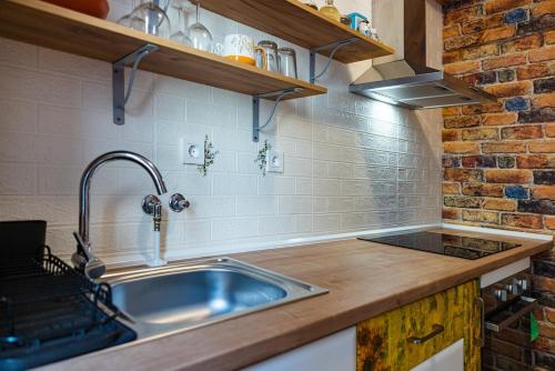 a kitchen with a sink and a brick wall at Studio Apartma Leopold in Piran