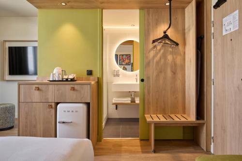a bedroom with a bed and a bathroom with a sink at Hampton By Hilton Lyon Airport in Colombier-Saugnieu