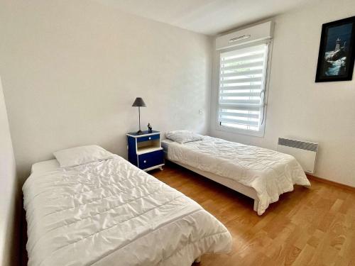 a bedroom with two beds and a nightstand and a window at Appartement moderne 2 pièces avec grand balcon à Étel, proche plage - FR-1-479-166 in Étel