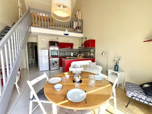 une salle à manger avec une table et une cuisine dans l'établissement Duplex confortable avec climatisation près du port et plages d'Étel - FR-1-479-204, à Étel
