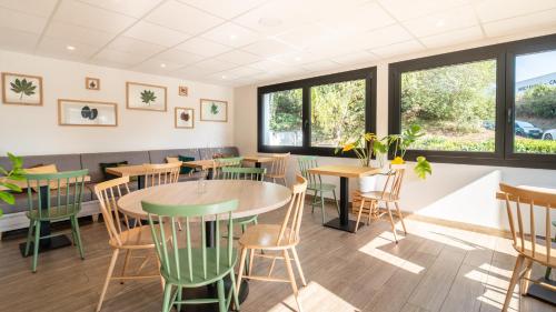 a restaurant with tables and chairs and windows at Campanile Limoges Nord in Limoges