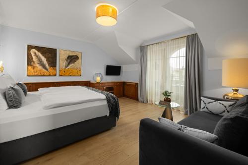 a hotel room with a bed and a couch at Wellness- & Sporthotel Jagdhof in Röhrnbach