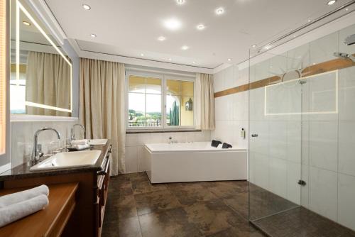 a bathroom with a tub and a sink and a shower at Wellness- & Sporthotel Jagdhof in Röhrnbach