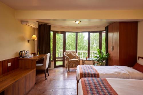 a hotel room with two beds and a desk at Dhulikhel Lodge Resort in Dhulikhel