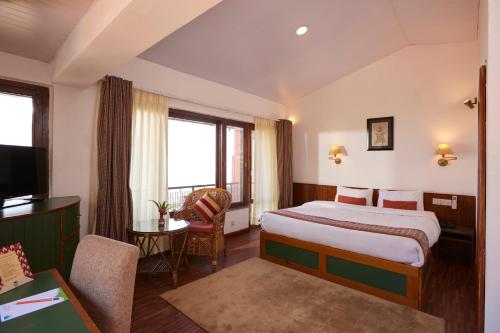 a hotel room with a bed and a desk and window at Dhulikhel Lodge Resort in Dhulikhel