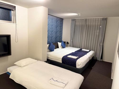 a hotel room with two beds and a tv at HOTEL MASTAY jingumichi in Kyoto