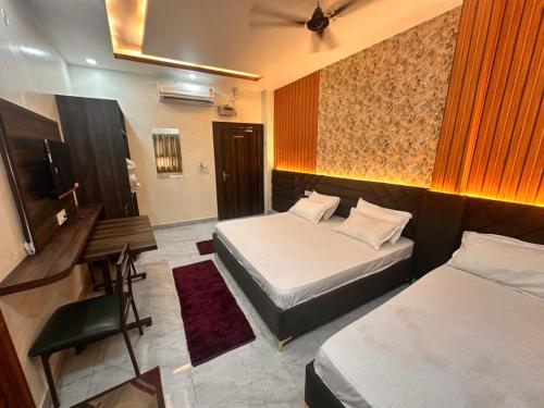 a room with two beds and a desk and a television at Hotel Shri Chandrawala in Ayodhya