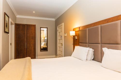 a bedroom with a large white bed and a mirror at Premier Resort Mpongo Private Game Reserve in Macleantown