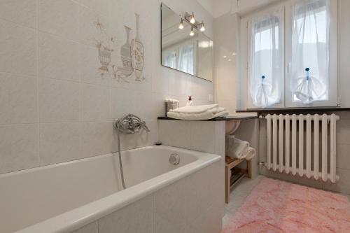 a white bathroom with a tub and a mirror at La Villa di Ludo in San Cassiano