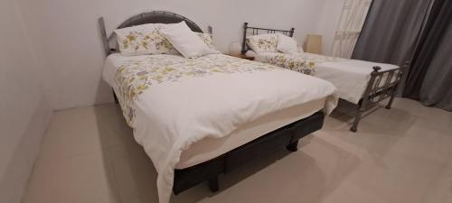 a bedroom with two beds with white blankets and pillows at By The Bay Oracabessa Queen Bedroom Suite in Oracabessa