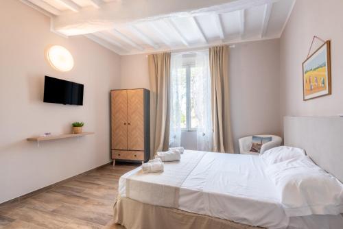 a bedroom with a white bed and a tv at L'arco del pellegrino in Monteroni dʼArbia