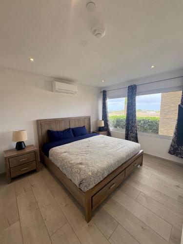 ein Schlafzimmer mit einem Bett und einem großen Fenster in der Unterkunft Sunset Bliss Suite at Commandeurs in Oranjestad