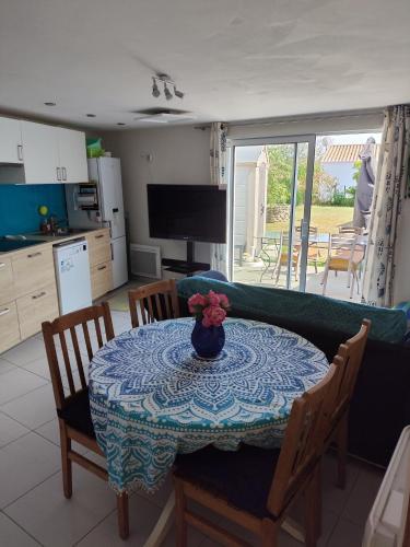 une table de salle à manger avec un vase de fleurs dessus dans l'établissement L'ampli sur jardin, à Noirmoutier-en-l'lle