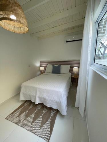 a white bedroom with a bed and a window at Bella Palm Beach in Palm-Eagle Beach