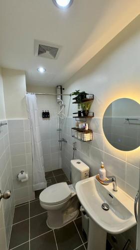 a white bathroom with a toilet and a sink at The A&R Stay-Mactan in Mactan