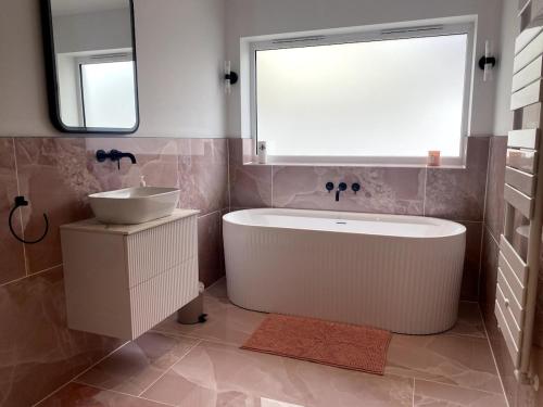 a bathroom with a tub and a sink and a window at Detached Home Near Kings Lynn in North Runcton
