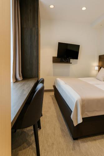 a hotel room with a bed and a flat screen tv at Central Konaci Apartments & Studio by Husky in Kopaonik