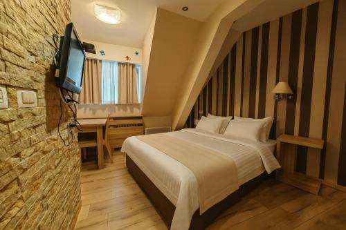 a hotel room with a bed and a television at Central Konaci Apartments & Studio by Husky in Kopaonik