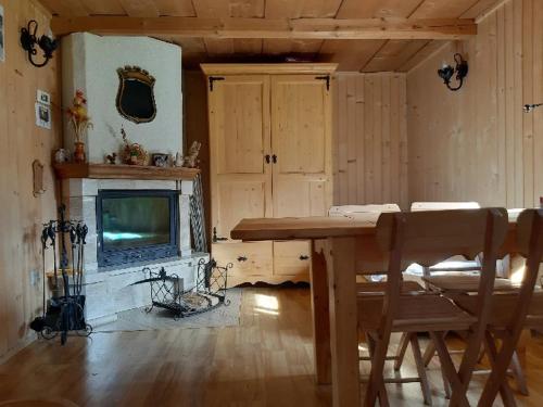 un soggiorno con tavolo in legno e camino di Kubusiowa Chatka a Murzasichle