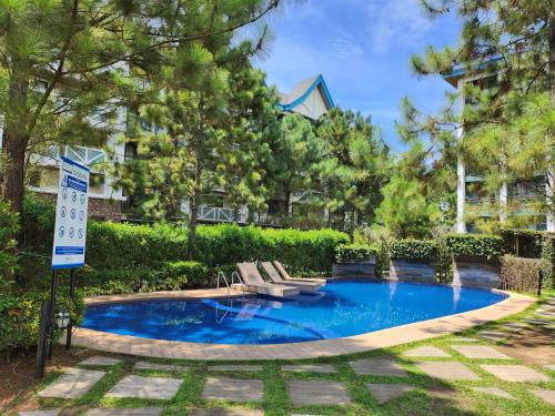 - une piscine avec 2 chaises longues devant un bâtiment dans l'établissement Pine Suites Tagaytay, à Tagaytay