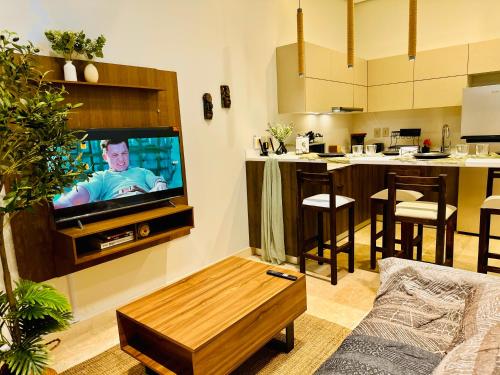 a living room with a flat screen tv and a kitchen at Jungle Guardian - Rooftop Pool & Beach Club in Zona Hotelera Tulum in Tulum