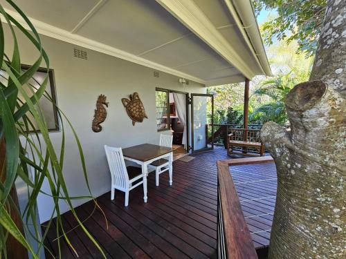 a porch with a table and chairs on it at Leopard Corner Lodge in St Lucia