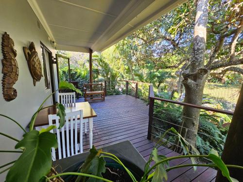 a porch with a table and chairs and a tree at Leopard Corner Lodge in St Lucia