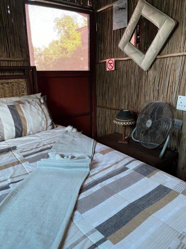 a bed in a room with a window and a fan at Moz Inn - Coconut View Resort in Lopes