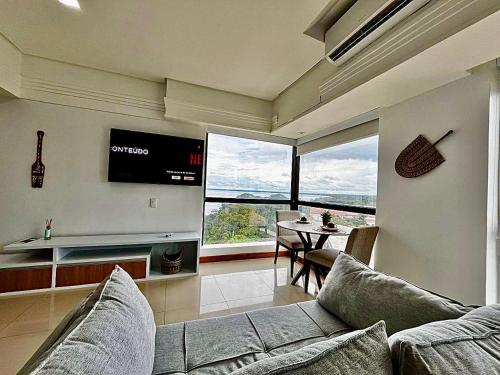 a living room with a couch and a tv and a table at 806 Suite Aquarela do Poente in Manaus
