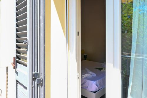 Puerta a una habitación con cama y ventana en Inn Pisa Rentals - Cozy flat by the airport, en Pisa