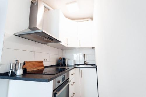 a kitchen with white cabinets and a stove top oven at 1 BR Apartment - ZENTRAL - BUSINESS - WIFI - KÜCHE - NETFLIX - PARKHAUS in Wiesbaden